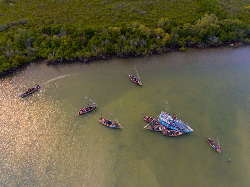 Uma foto aérea de barcos de pesca na Ilha Pate vendendo suas capturas para um barco comprador de peixes. Foto © M. Kirubi / TNC