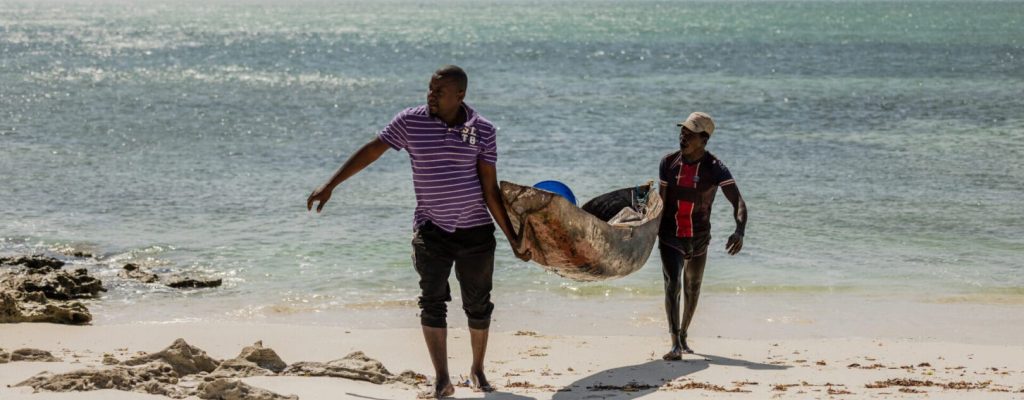 Fishers carry their canoes on to the high beach after a day of fishing